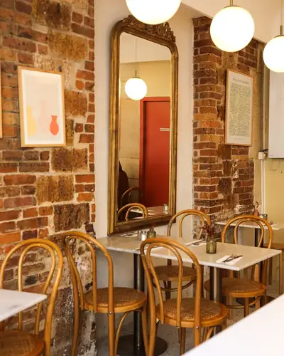 Dining room with brick walls and bistro chairs at the Oma coffee shop near République